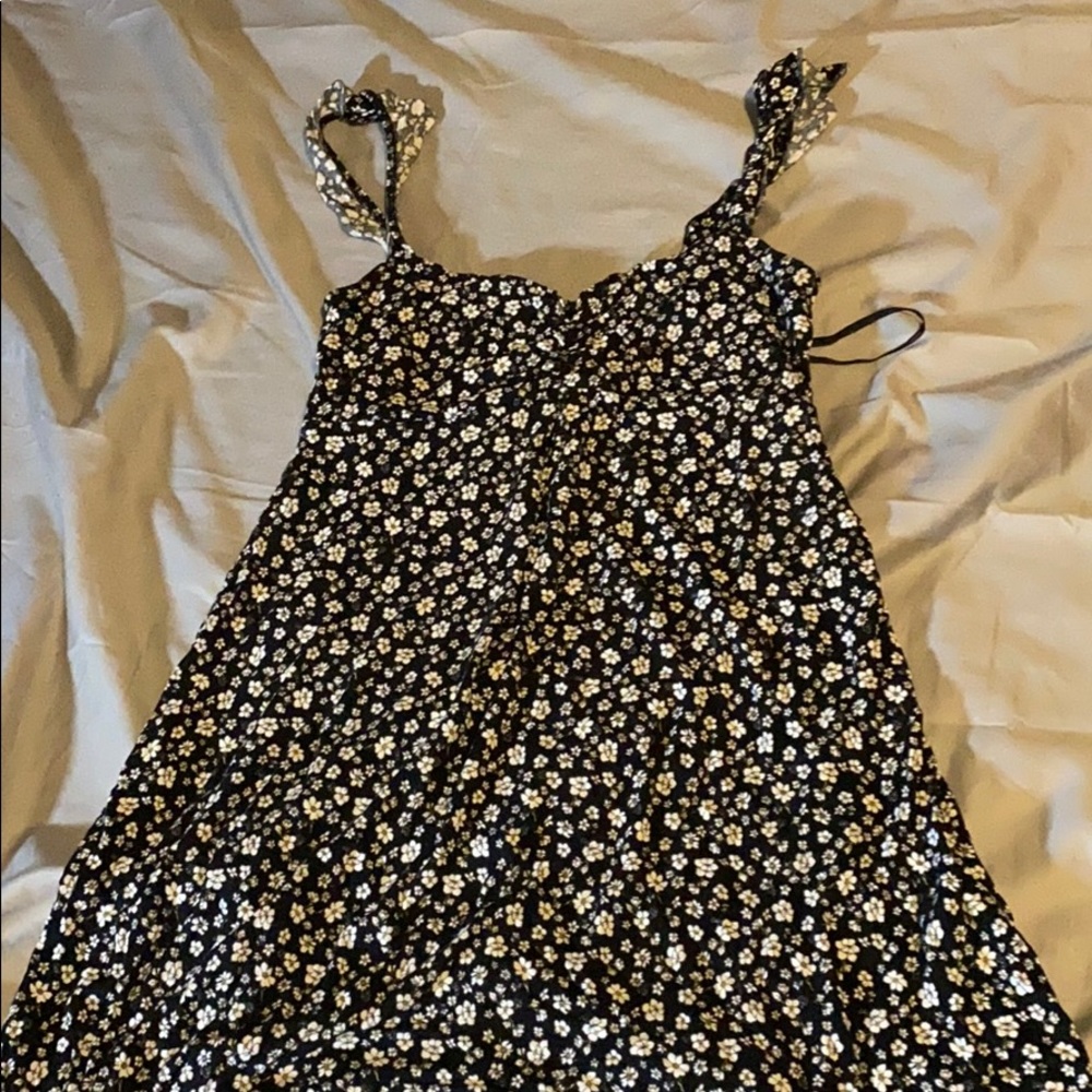 A black sundress covered in tiny sunflowers .